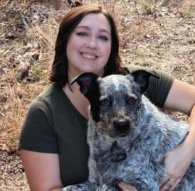 Happy woman with a blue merle Australian Cattle Dog outdoors.